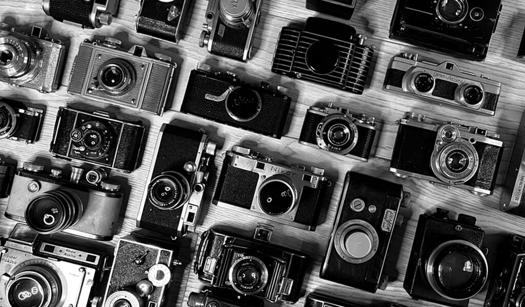 Black and white image showing many different cameras together.