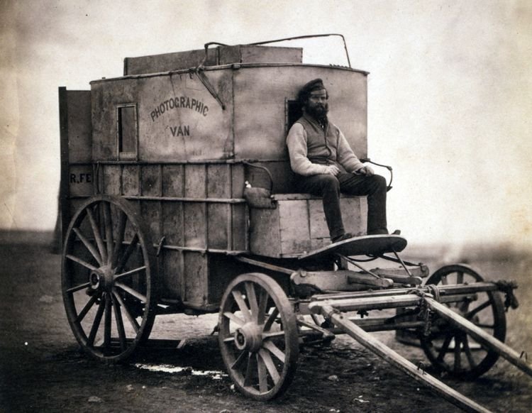 Old yellowish orangey brown vintage photograph showing a horse-drawn wagon.