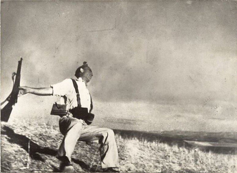 Robert Capa's Falling Soldier photo depicts a Republican soldier mid-fall, arms outstretched, rifle slipping, and a pained expression on his face, capturing the precise moment of being fatally shot during the Spanish Civil War.