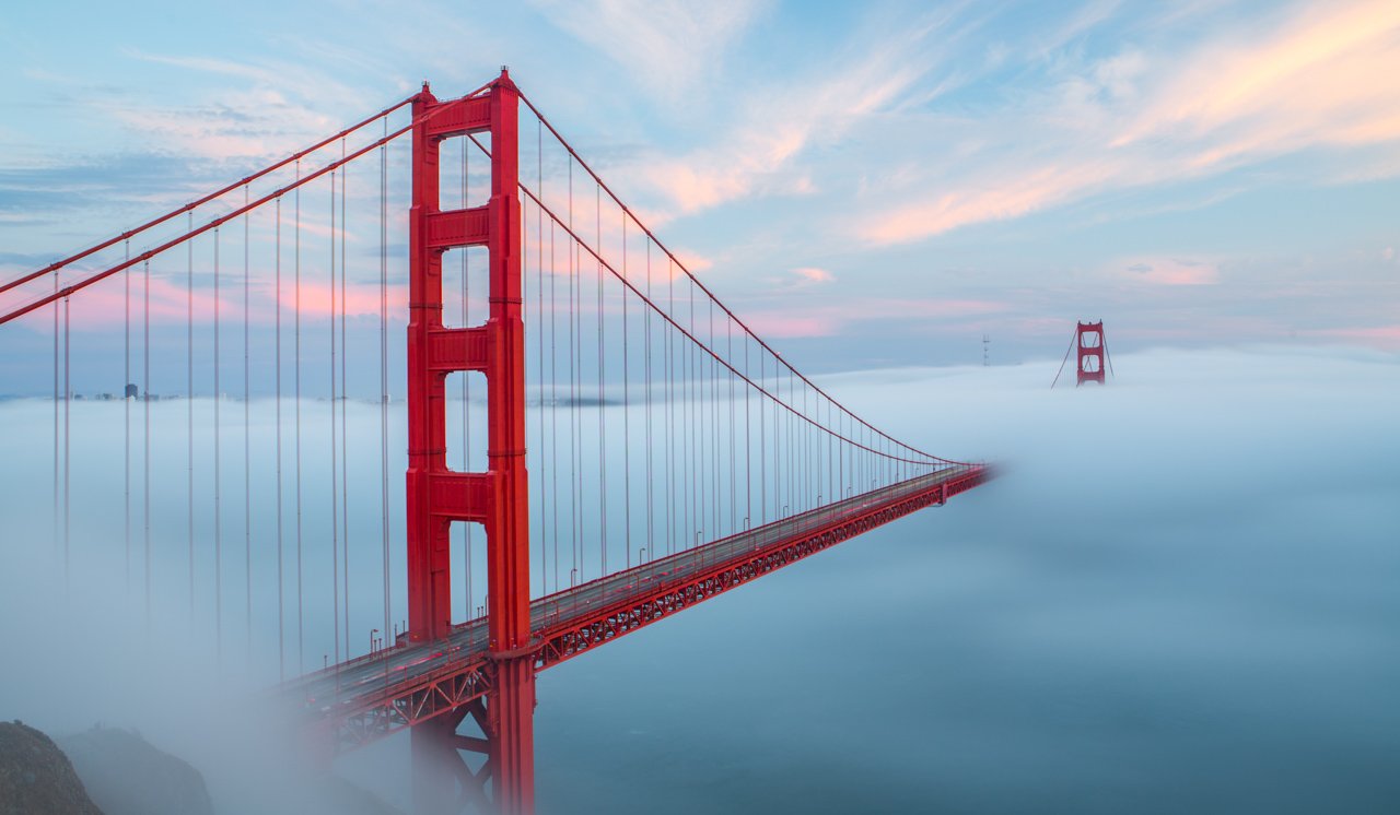 This photograpph shows the bridge towering above the clouds. You cannot even see the sea. It looks as if the bridge is on the clouds in the sky.