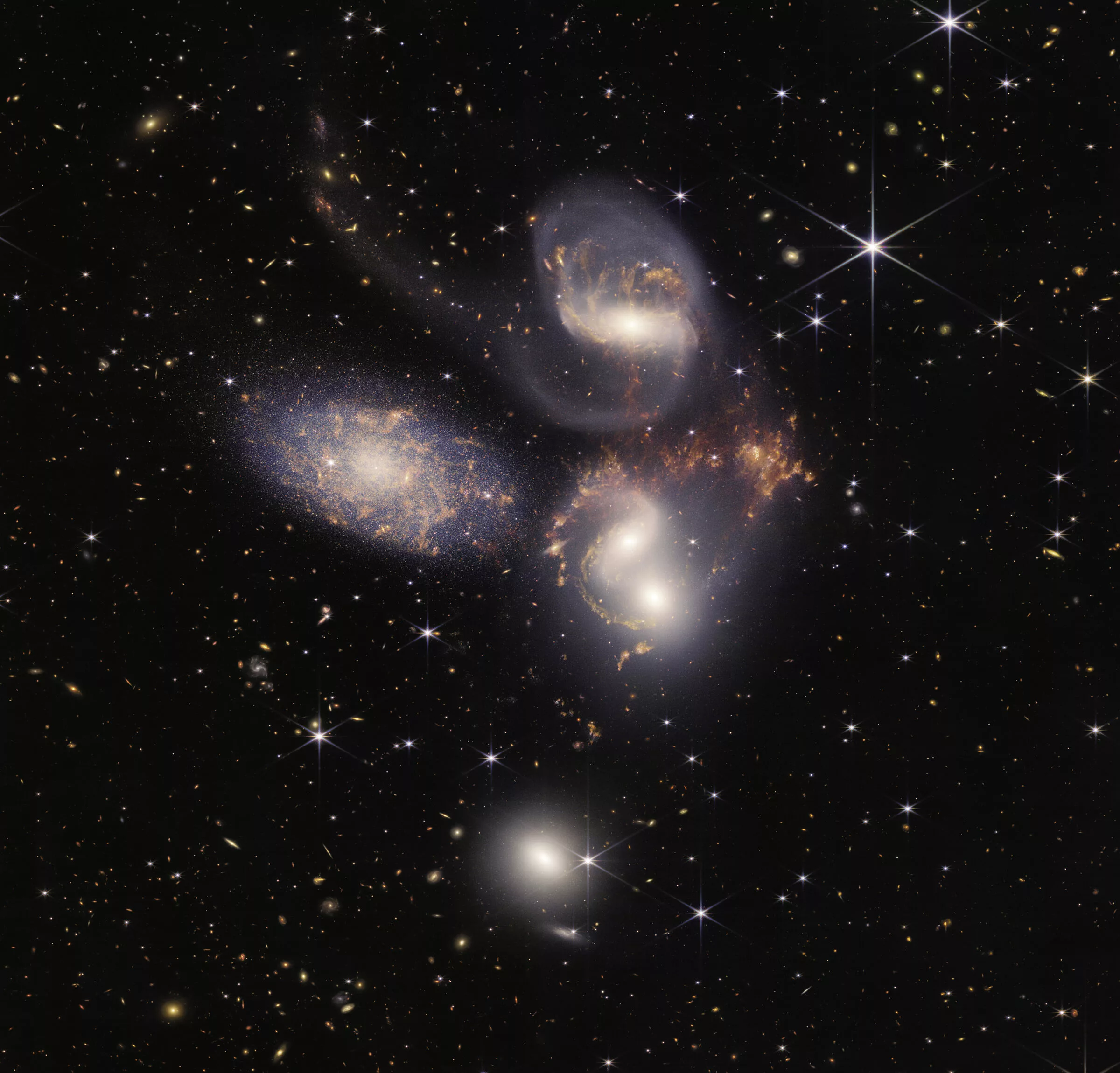 Image shows the Quintet of Galaxies. It looks like a group of galaxies, all huddled together. They look like a group of friends, all looking out into the universe. Their gasy wisps interwine.