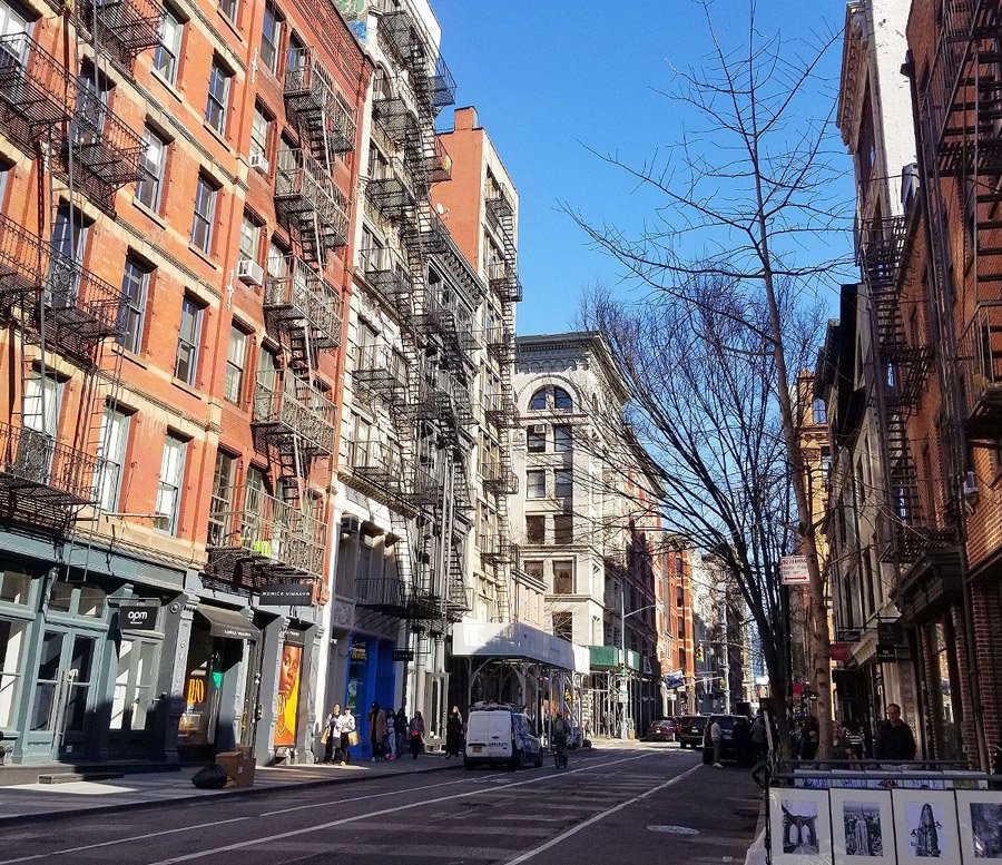 Photo of Soho area of New York. You can see the icnoic American style fire escape metal staircases on the sides of the buildings.