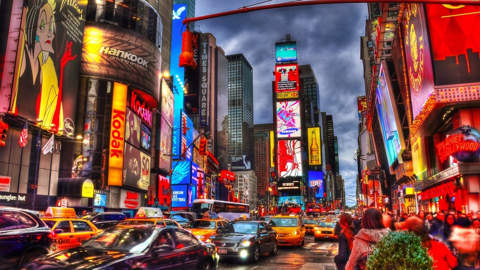 Photo shows Times Square today, in the evening when all the lights are glowing bright. Time Square in these mdoern times. It is filled with bright lights, marketing, advertisements everywhere. The streets are very busy. There are people everywhere.